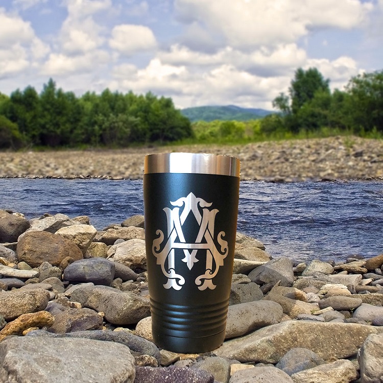 A black cup sitting on top of rocks near water.